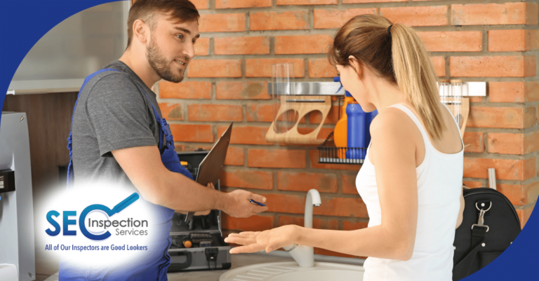 Inspector discussing home maintenance details with a homeowner in the kitchen.