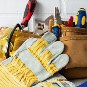 a set of tools and safety gear neatly arranged on a surface, including a pair of work gloves, safety goggles, and various hand tools like screwdrivers and pliers